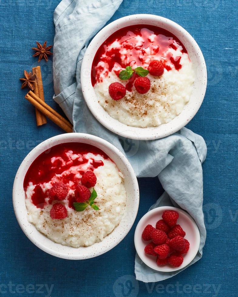 Rice pudding. French milk rice dessert with raspberries, blueberries, jam. Top view, vertical photo