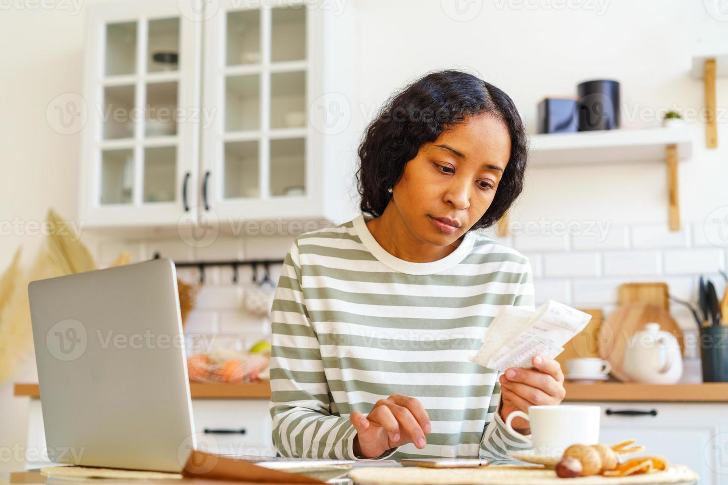 mujer afroamericana pagando facturas. lidiar con la contabilidad en el teléfono inteligente. contabilidad remota foto