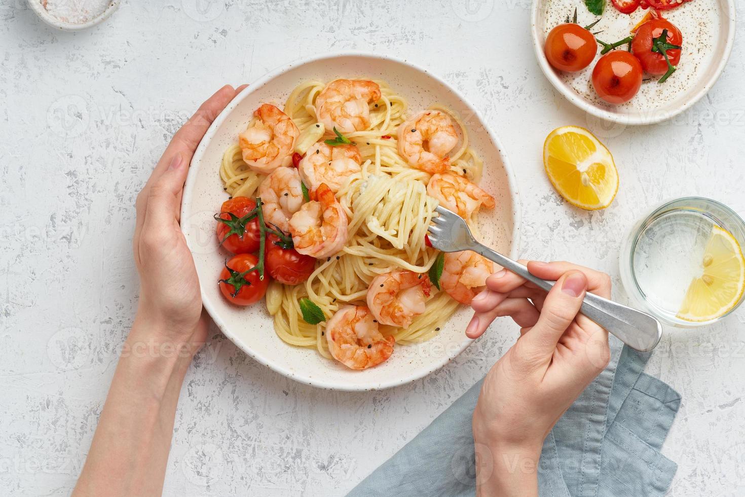 Pasta bavette with fried shrimps, bechamel sauce. Woman hands in frame, girl eats pasta, top view photo