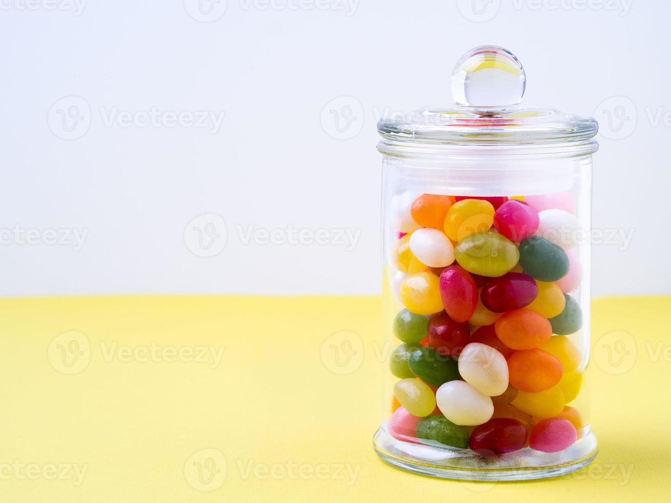 frasco de vidrio lleno de dulces y caramelo, con la tapa cerrada sobre la mesa foto