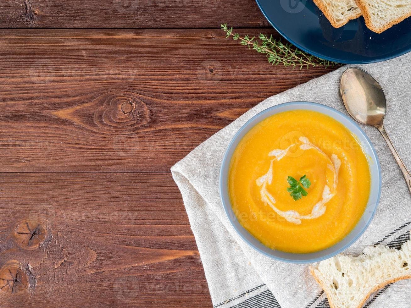 Dietary vegetarian pupmkin cream soup puree, on dark brown wooden table, top view, copy space, close up. photo