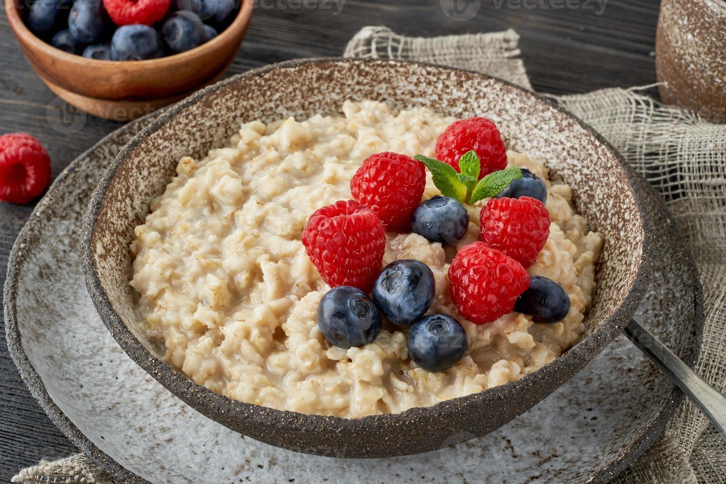 Oatmeal rustic porridge with blueberry, raspberries in ceramic vintage bowl, dash diet with berries photo