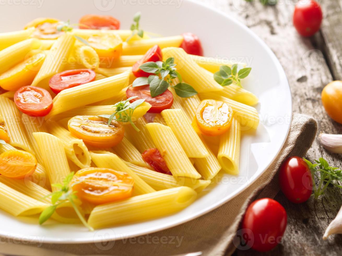 Penne pasta with tomatoes and basil on old rustic gray wooden background, low-calorie diet, top view, close-up photo