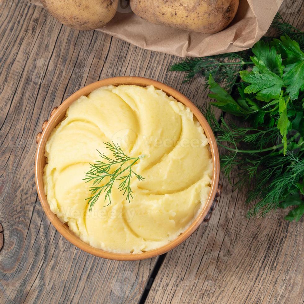 Mashed potatoes, boiled puree in brown bowl on dark wooden rustic background, top view photo