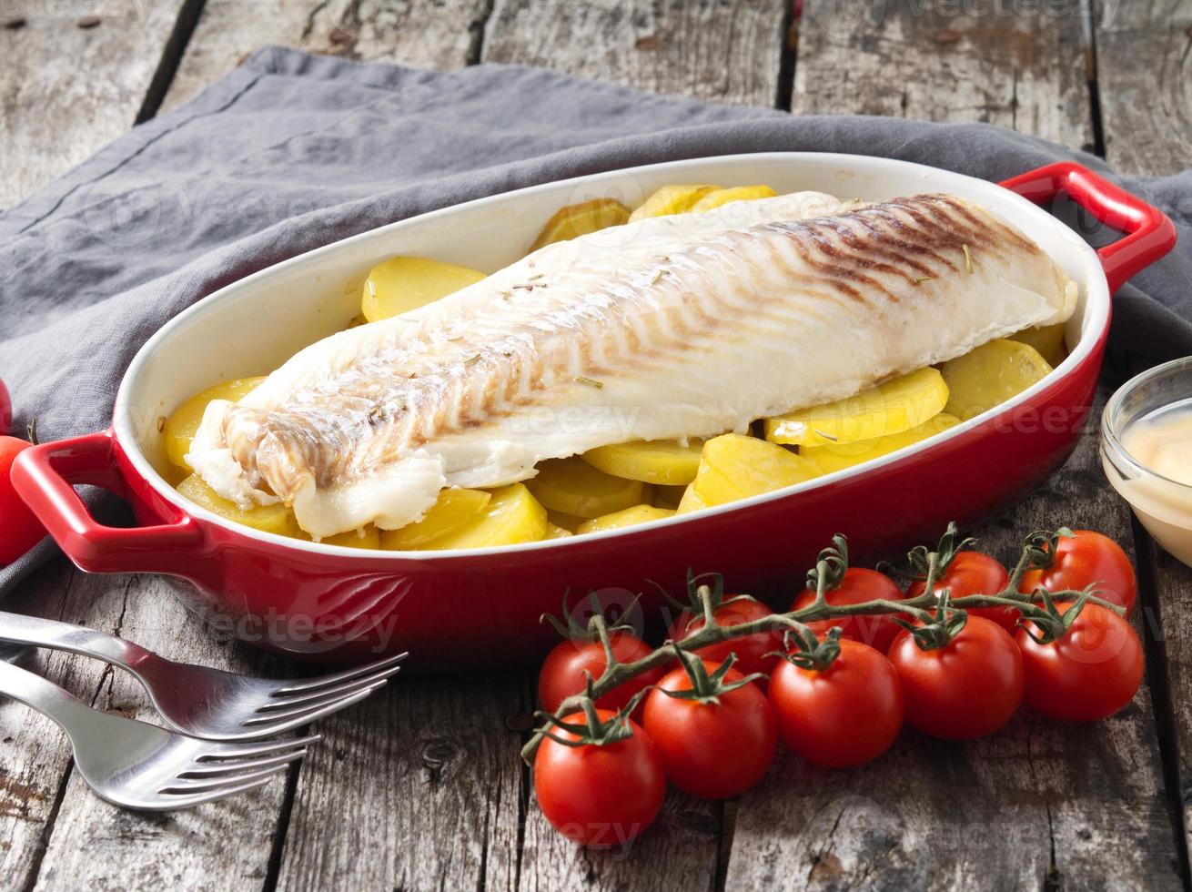 Fish cod baked in the oven with potatoes, diet healthy food. Dark old wooden rustic gray background, side view photo