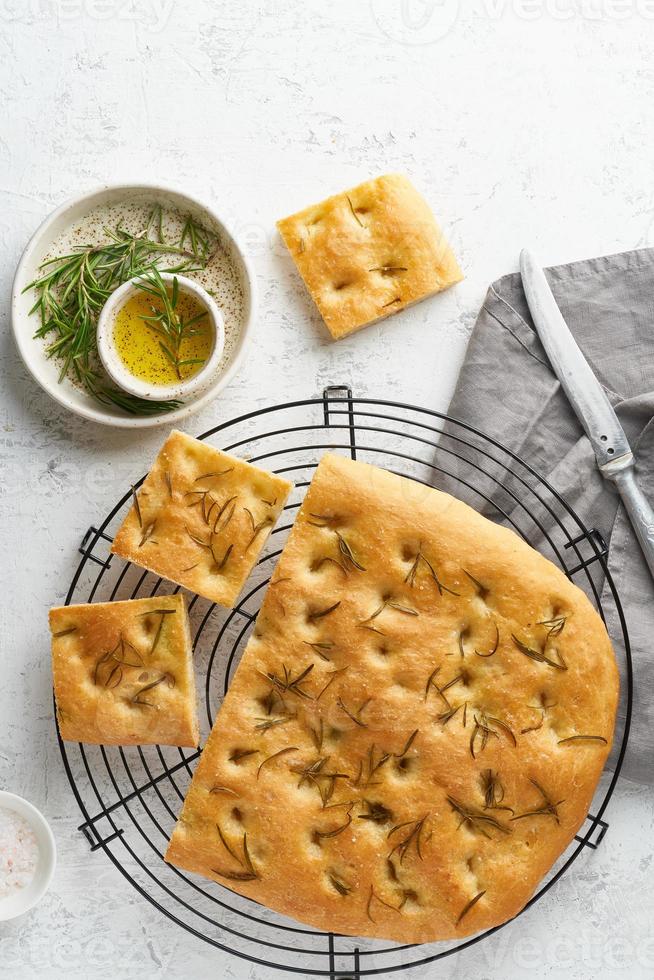 Focaccia, pizza, italian flat bread with rosemary and olive oil on grid photo