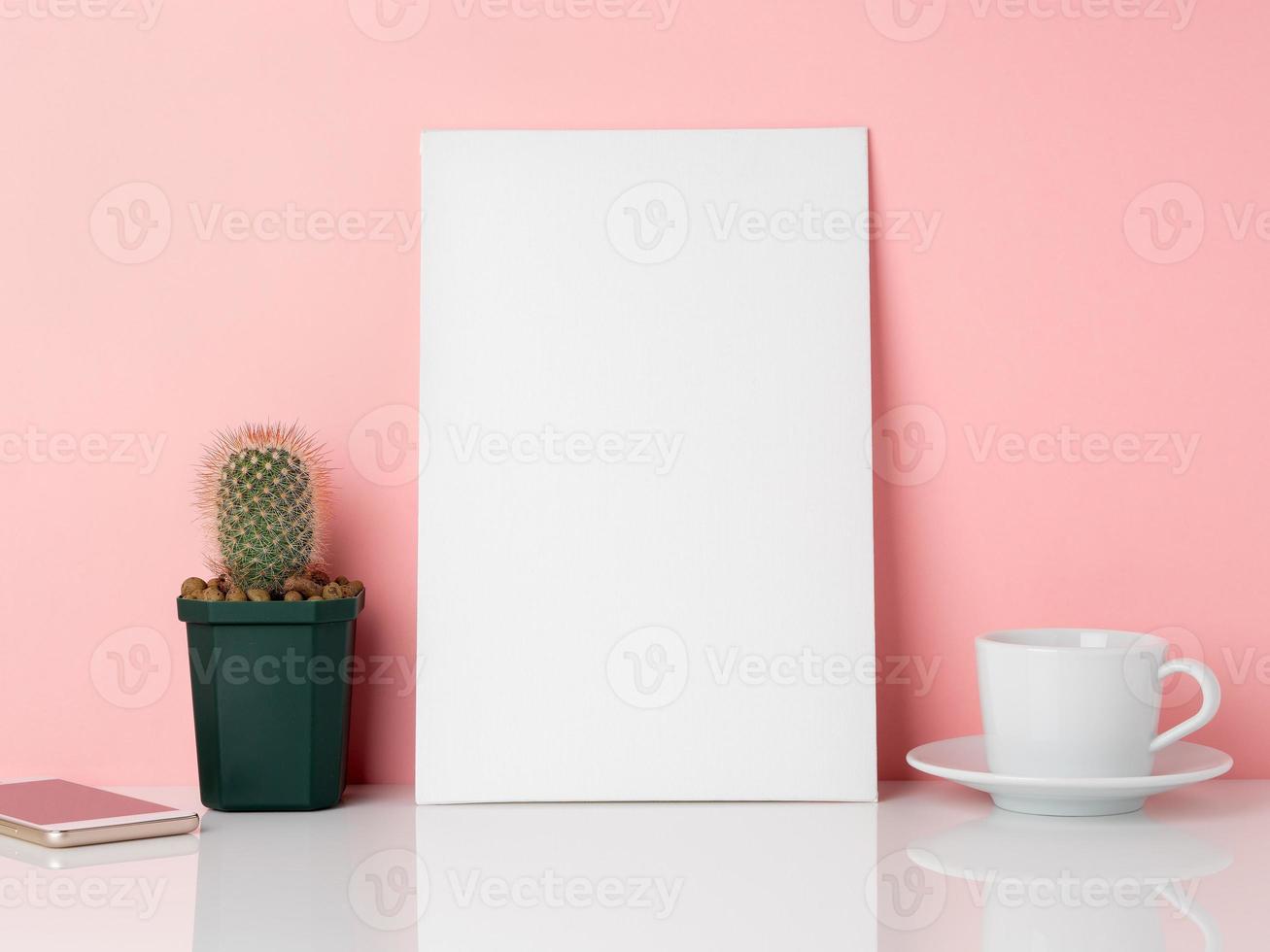 Blank white frame and plant cactus, cup of coffee or tea on a white table against the pink wall with copy space. Mockup with copy space. photo