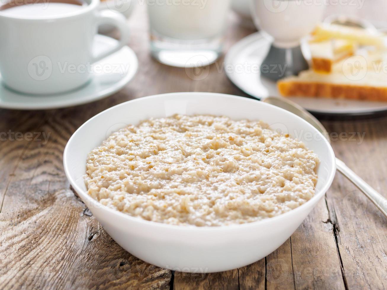 Large bowl of tasty and healthy oatmeal for Breakfast, morning meal. Side view, close up, wooden rustic table. photo