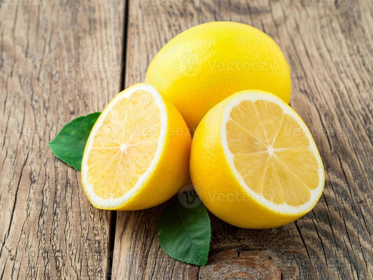 fresh lemon and cut off half on wooden old table, side view photo