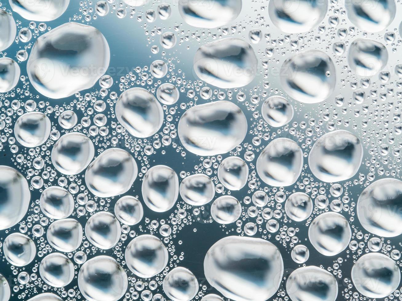 Abstract gray background with large and small spherical convex drops of water on glass. Bubbles on window. Macro, close up. photo