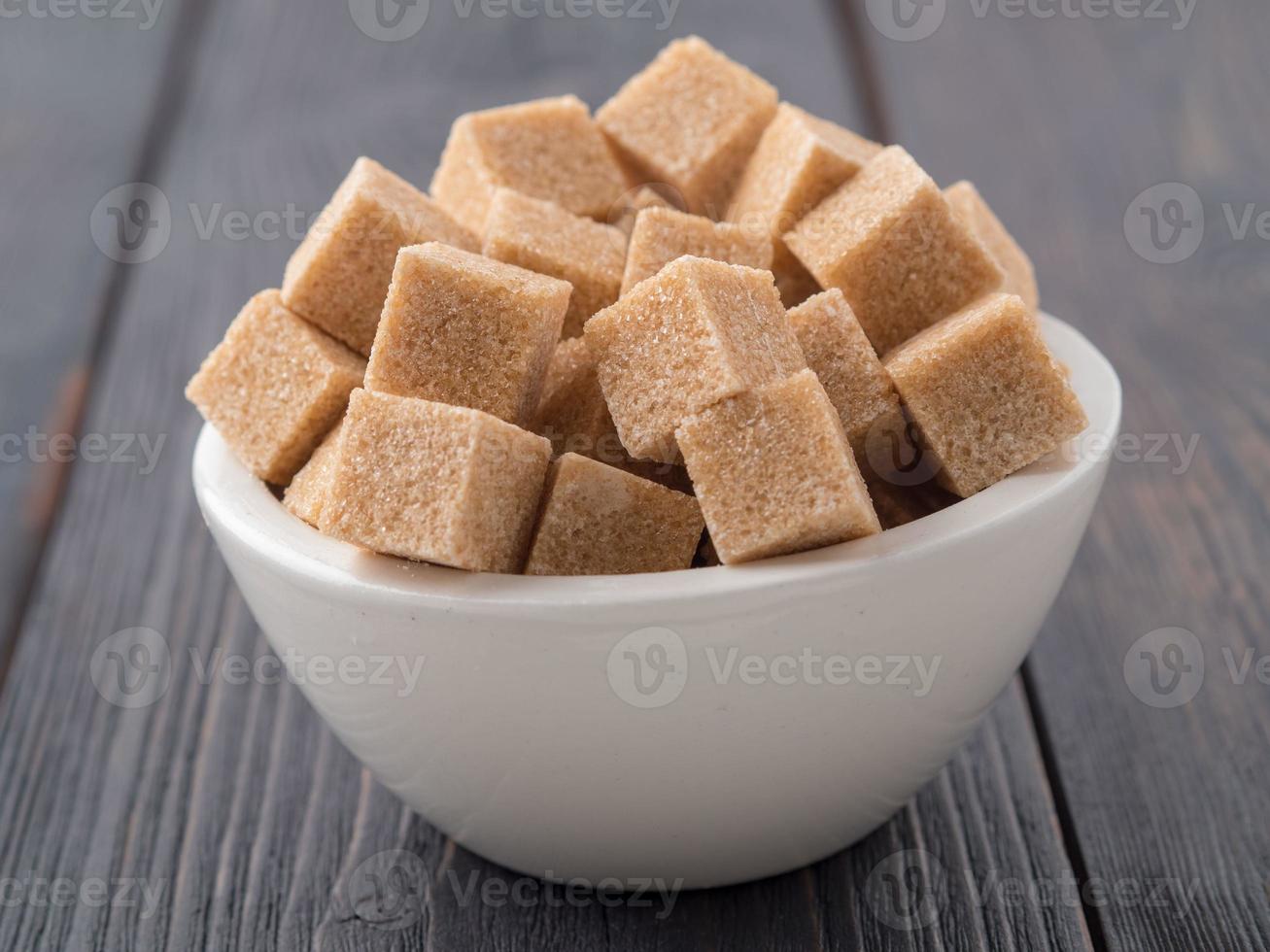 brown cane sugar in a white Cup on a brown wooden background, side view photo