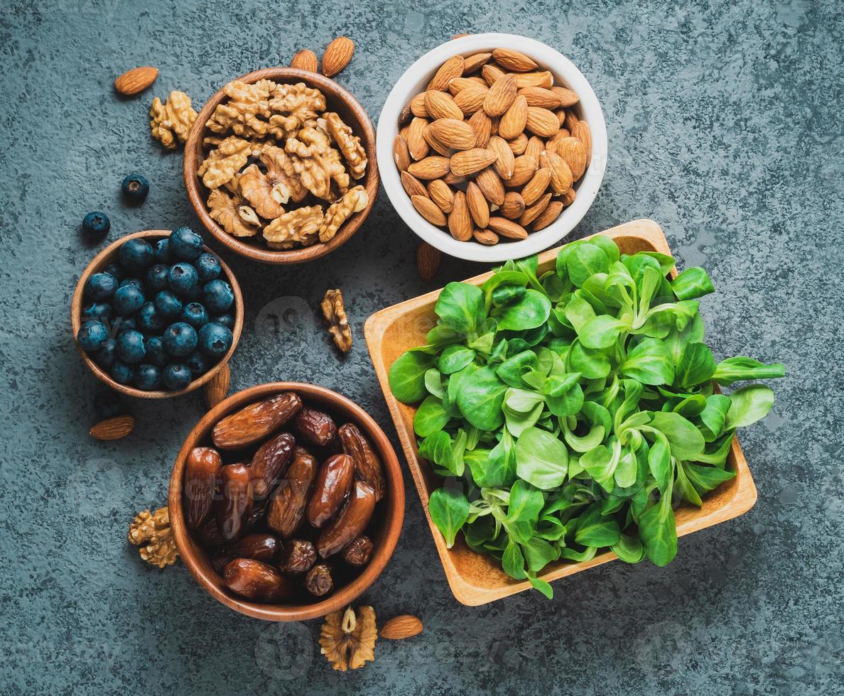 Healthy vegan food - dry fruits, greens, nuts, berry. Superfoods on gray stone background, top view. photo