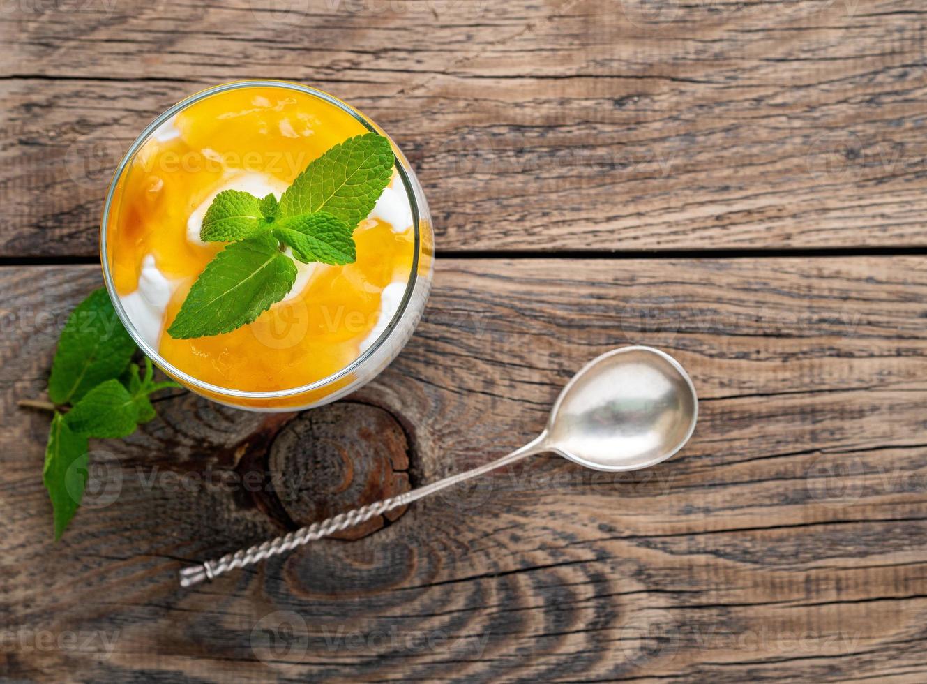Healthy layered dessert with yogurt, banana, mango , cracker on wooden background, top view. photo