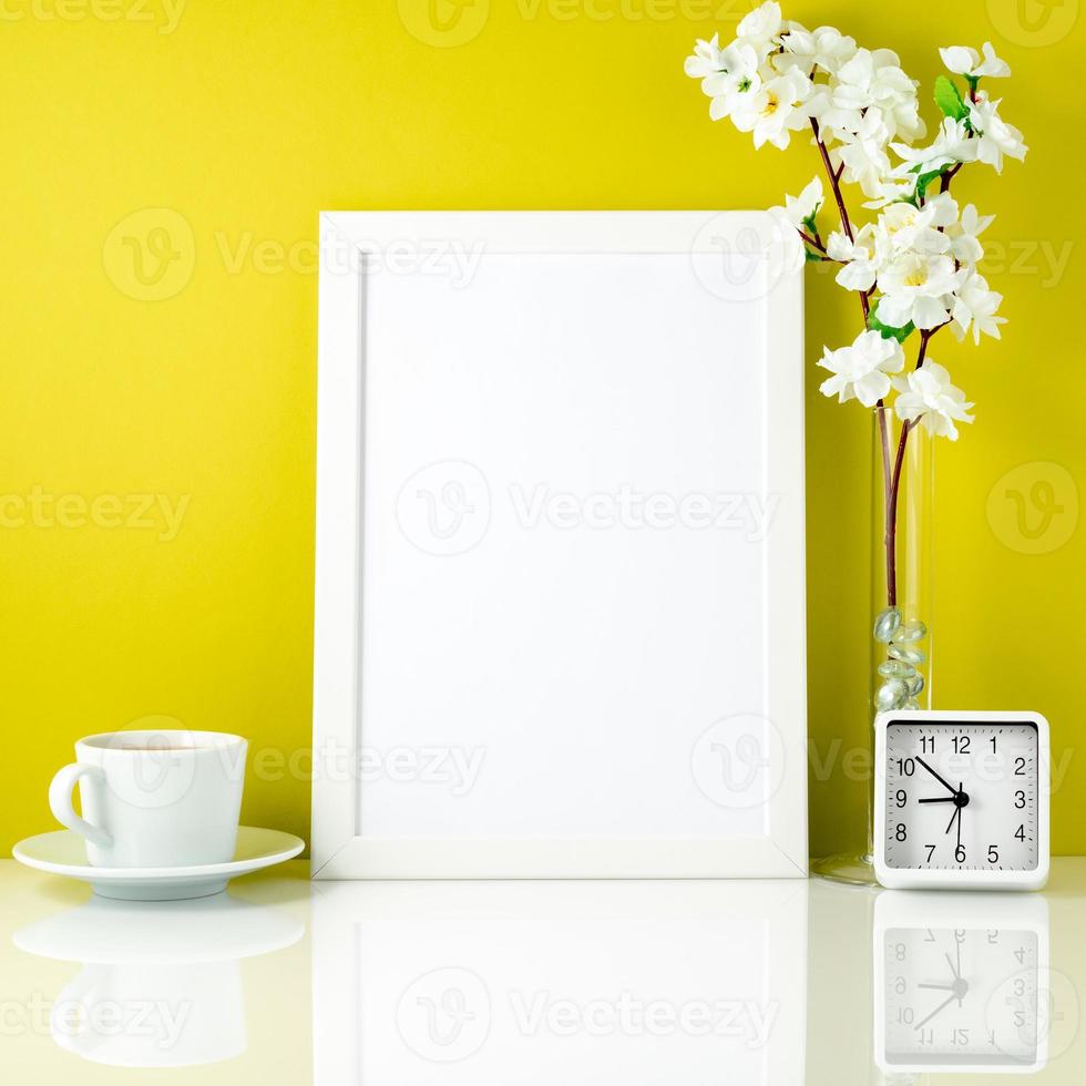White frame, flower in vase, cup with tea or coffee, clock on wh photo