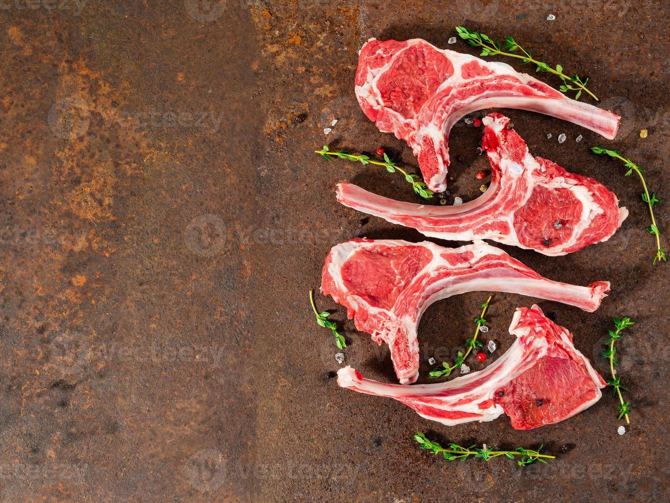 raw lamb cutlets on bone on dark metallic background, top view, empty space. photo