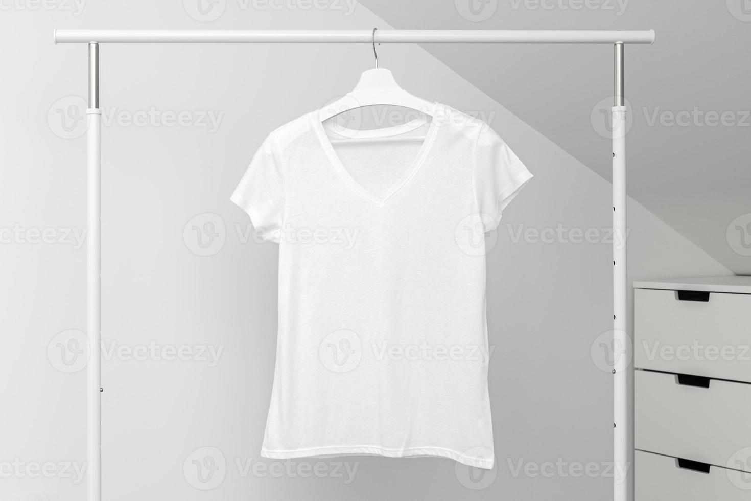 Group of Assorted t-shirts hanging on white hangers. Clothing rack photo