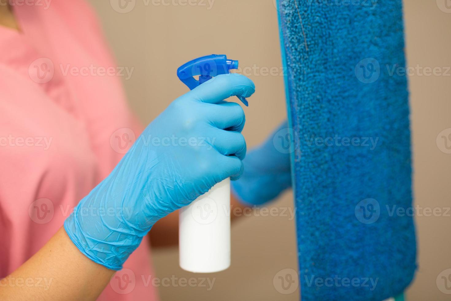 Person, a hand in a blue rubber glove in the picture, removes and washes bathroom sink photo