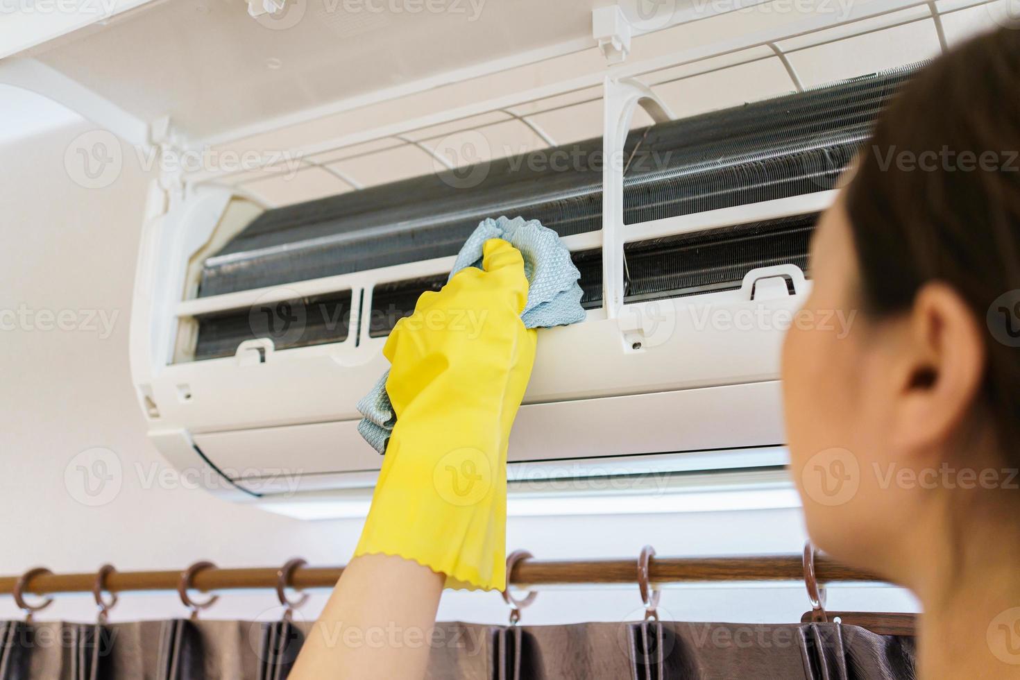 mujer asiática limpiando un filtro de aire acondicionado sucio y polvoriento en su casa. ama de casa quitando un filtro de aire acondicionado polvoriento. foto