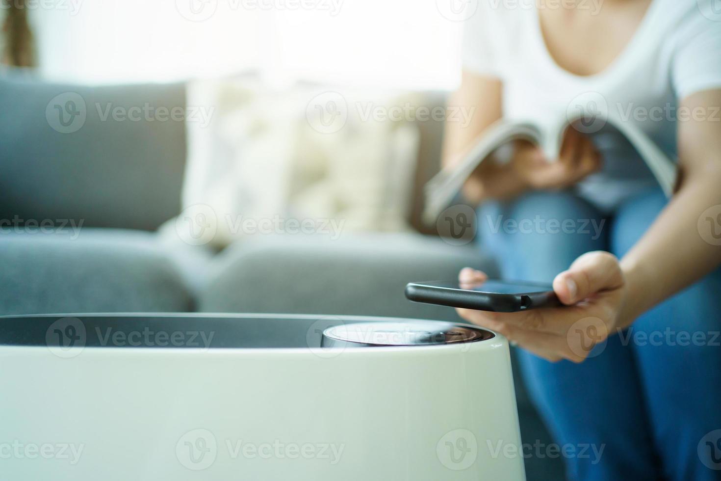 Woman control a modern air purifier through the application on a smartphone, a smartphone screen isolated in white color. Modern and smart home connectivity technology concept. photo
