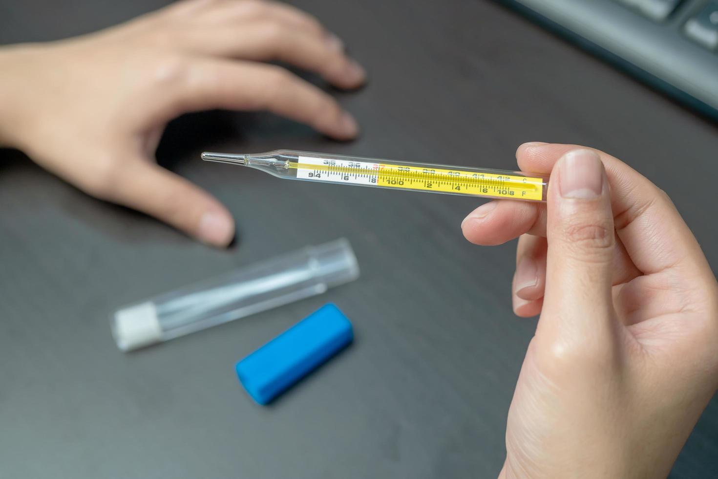 woman hand holding clinical thermometer on working desk,After using the clinical thermometer and worry about coronavirus spread photo