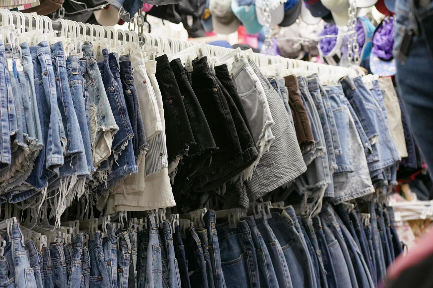 ropa usada colgada en una tienda de segunda mano en el mercado de fin de semana chatuchak bangkok, enfoque selectivo foto