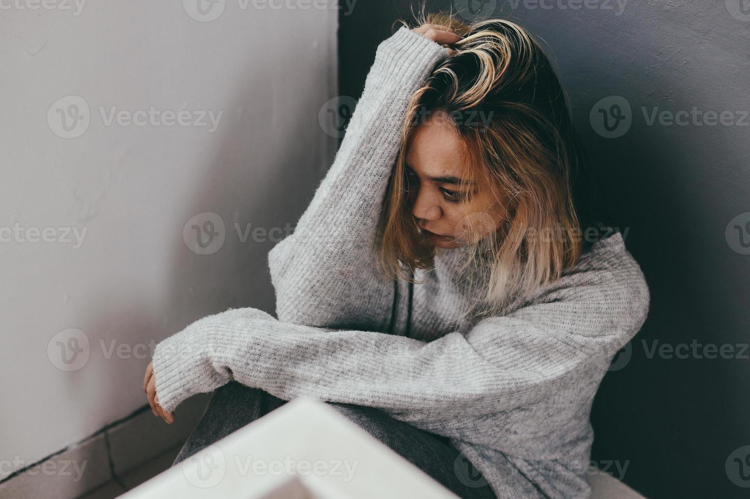Depressed and sad young woman sitting alone at home photo