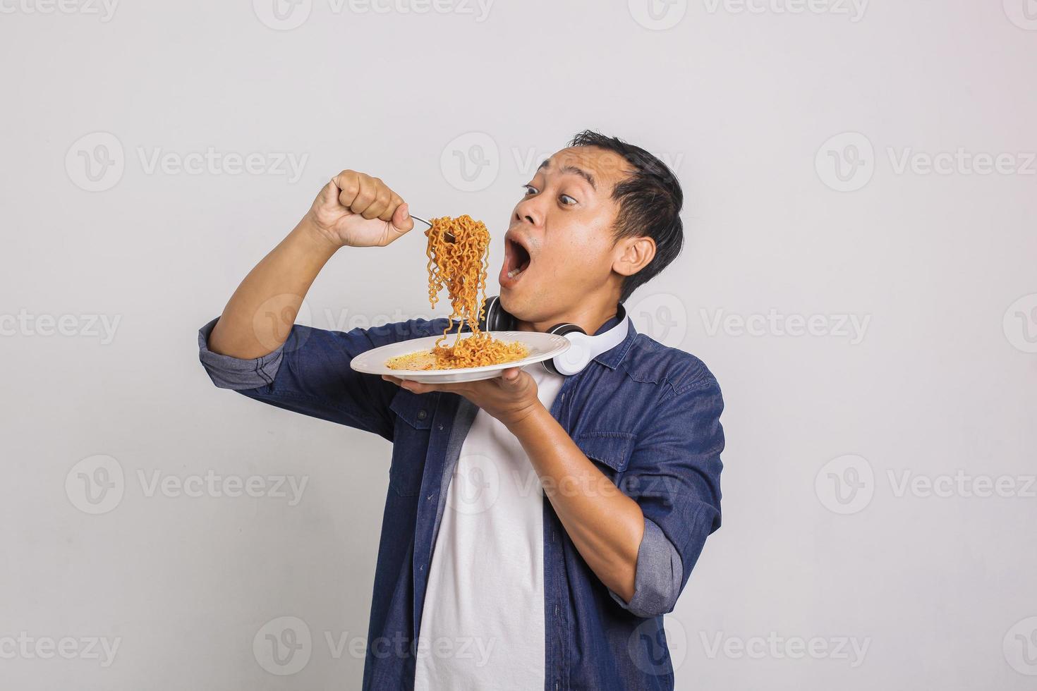 hombre asiático comiendo fideos instantáneos y se sorprende con lo delicioso que es foto