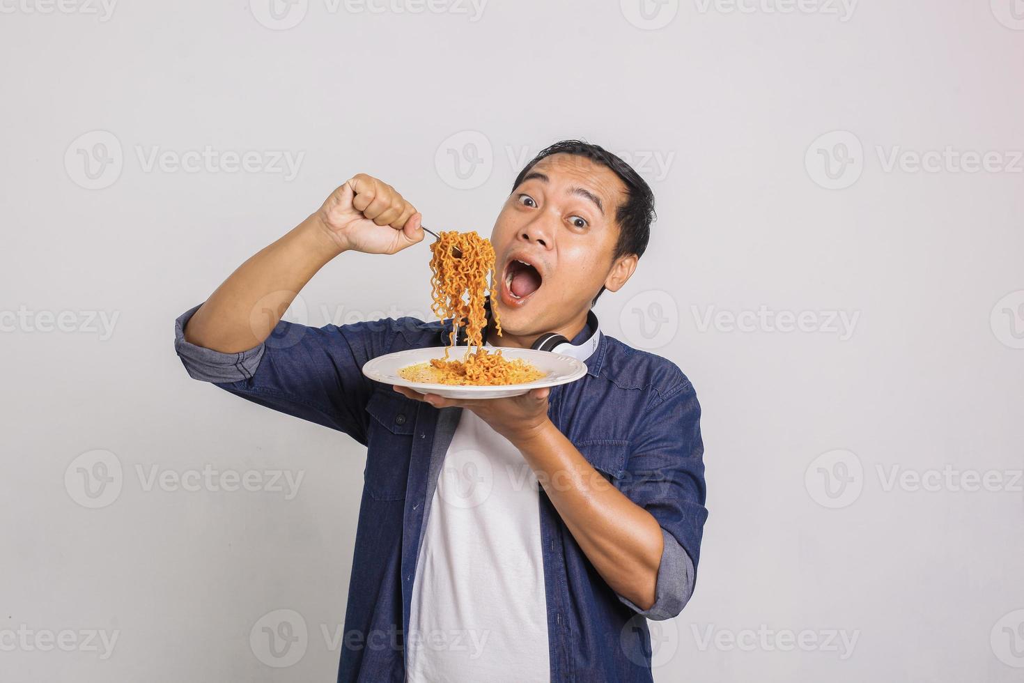 Asian man eating instant noodle and feel surprise with how delicious it is photo