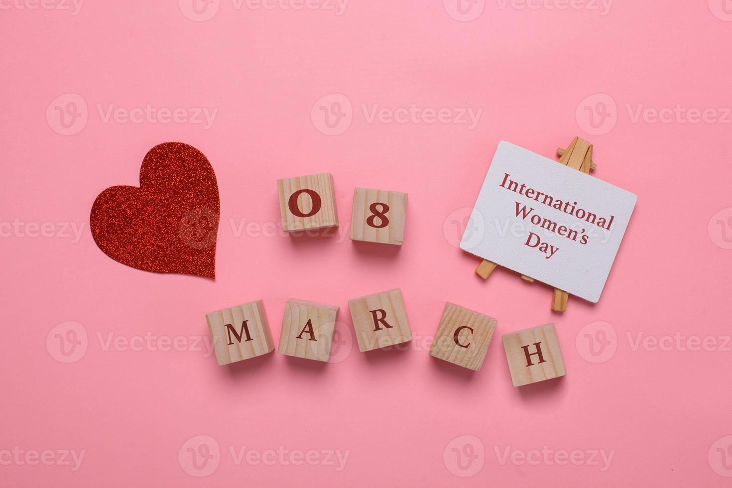 Creative Flat lay out of international women's day with sparkling red heart and 8 march on wooden cubes on pink background photo