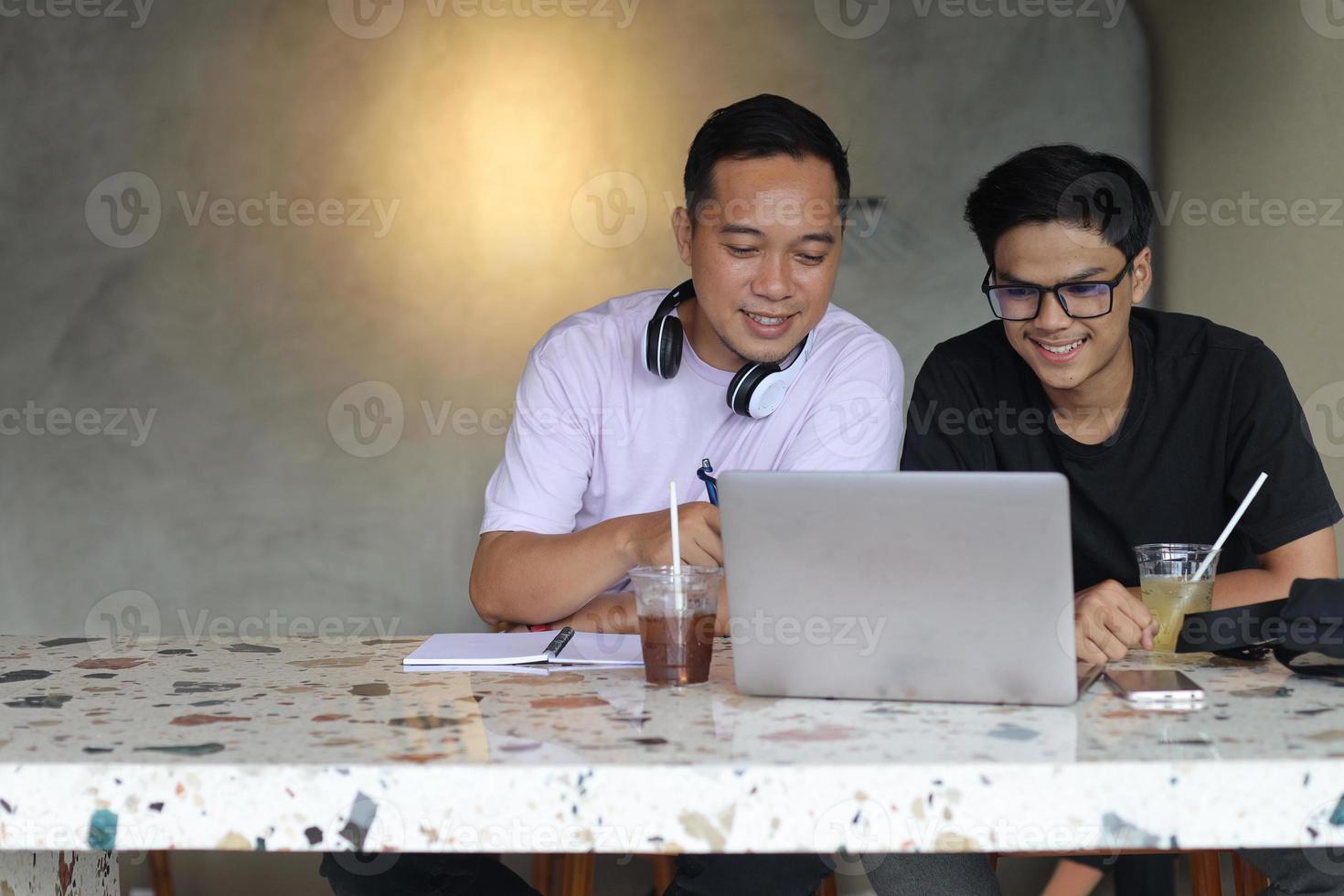 Two asian college students studying together using laptops in a cafe photo