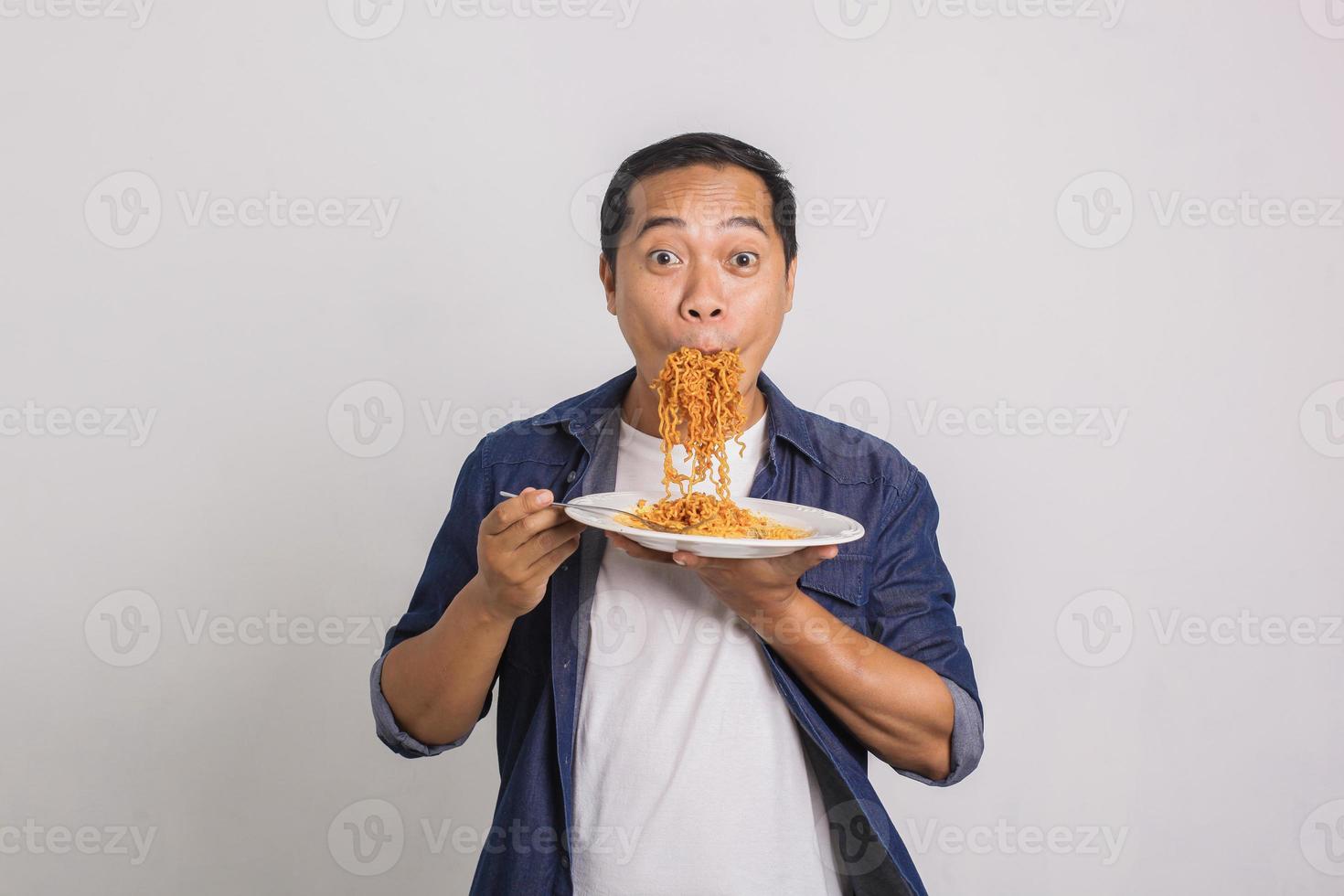 hombre asiático comiendo muchos fideos instantáneos y se sorprende con lo delicioso que es foto