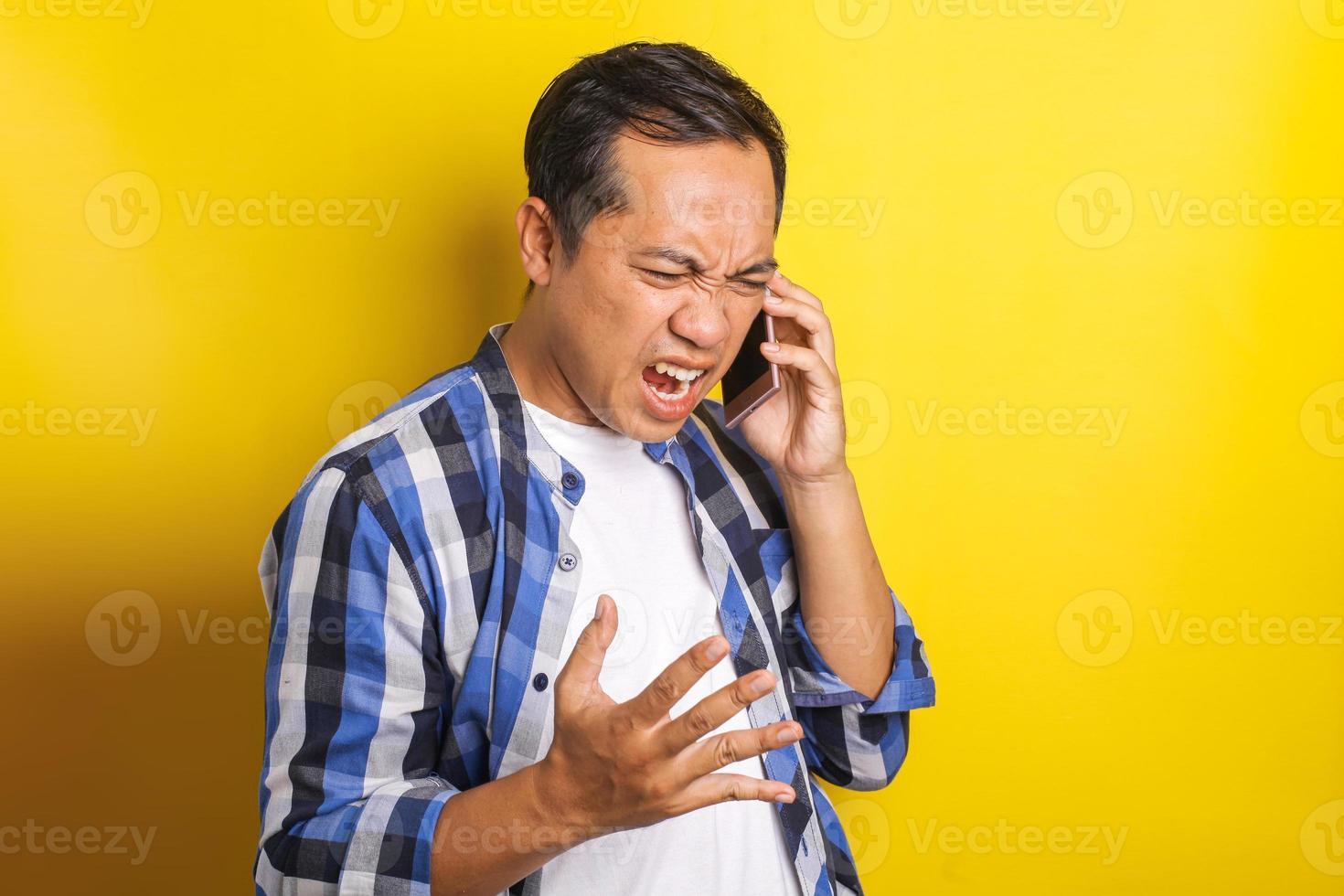 retrato de un hombre asiático enojado, gritando, molesto, por teléfono aislado de fondo blanco foto