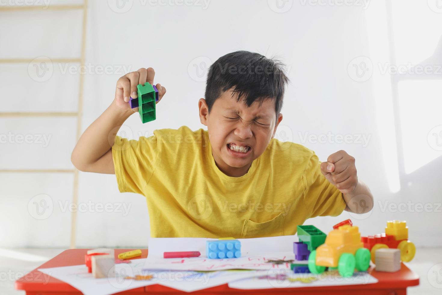 Emotional Tantrum and Angry boy while playing colorful bricks at home. Childhood traumatic experience, psychology, psychological, asperger syndrome, asperger's disorder, autistic, autism. photo