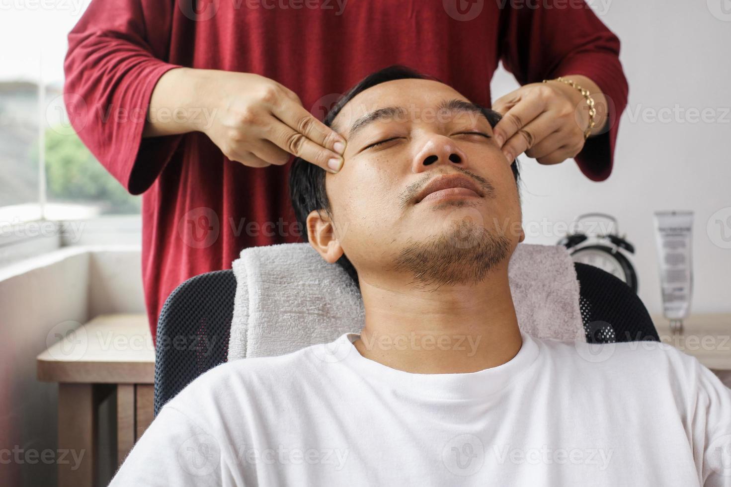 hombre asiático con masaje facial en el salón de spa foto