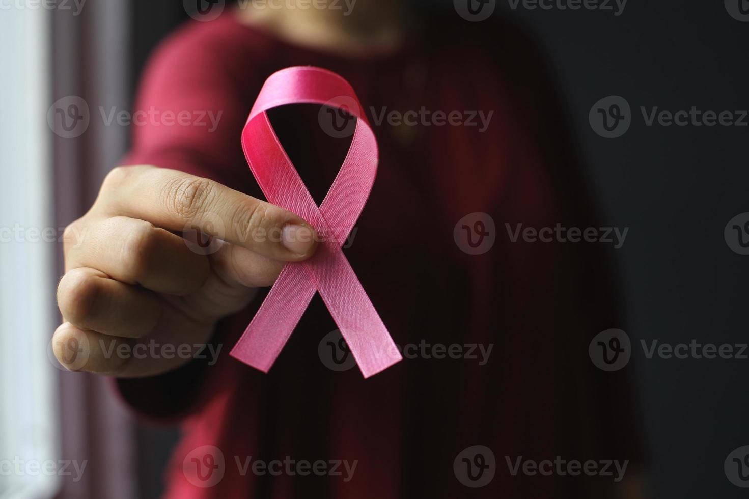 mano que sostiene la cinta rosa para el día mundial del cáncer y la concienciación sobre el cáncer de mama foto