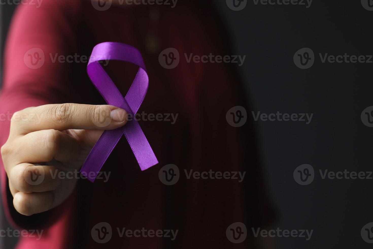 mano que sostiene la cinta morada para la enfermedad de alzheimer, cáncer de páncreas, conciencia de la epilepsia, día mundial del cáncer foto