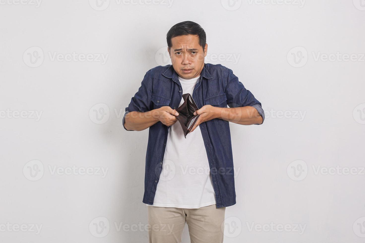 Portrait of sad handsome asian man showing contents of his wallet isolated on white background photo
