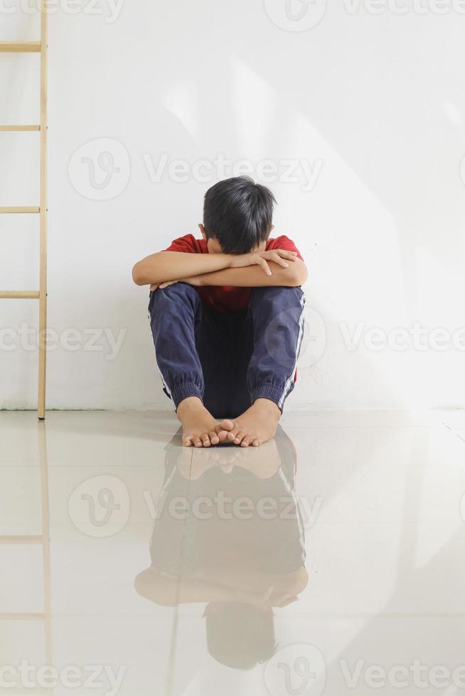 Sad and lonely child sitting on the floor against the wall. Childhood traumatic experience, psychology, psychological, asperger syndrome, asperger's disorder, autistic, autism. photo