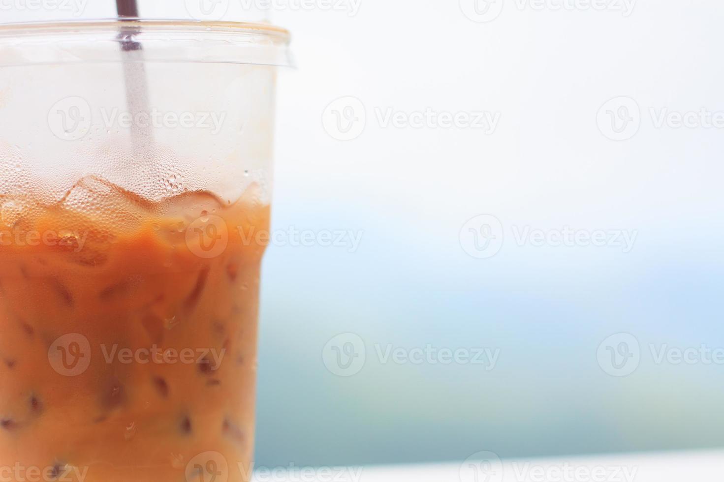 café helado con paja en vaso de plástico con fondo natural foto