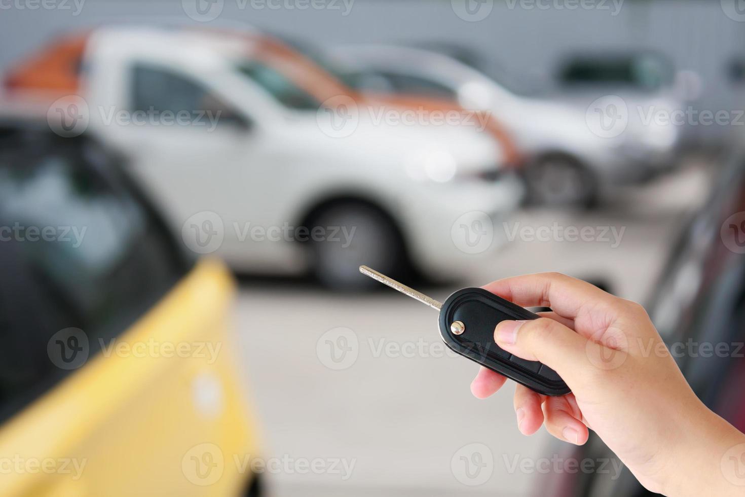 Hand hold car key remote on blur car parking photo