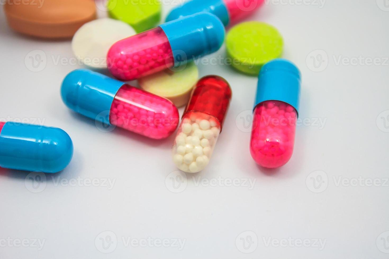 Colored pills, tablets and capsules on white background photo