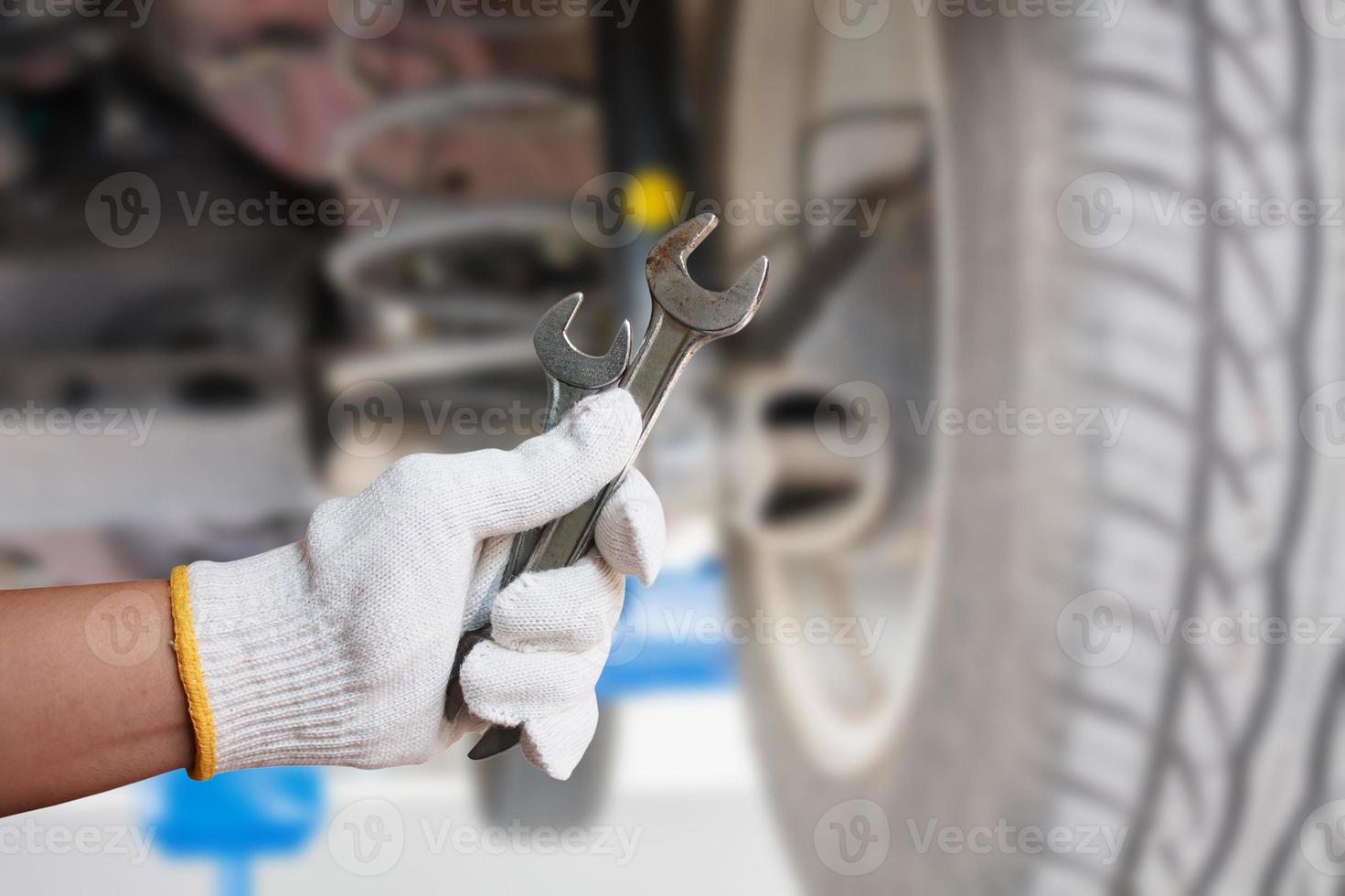 mecánico de automóviles sosteniendo una llave en el garaje de reparación de automóviles foto