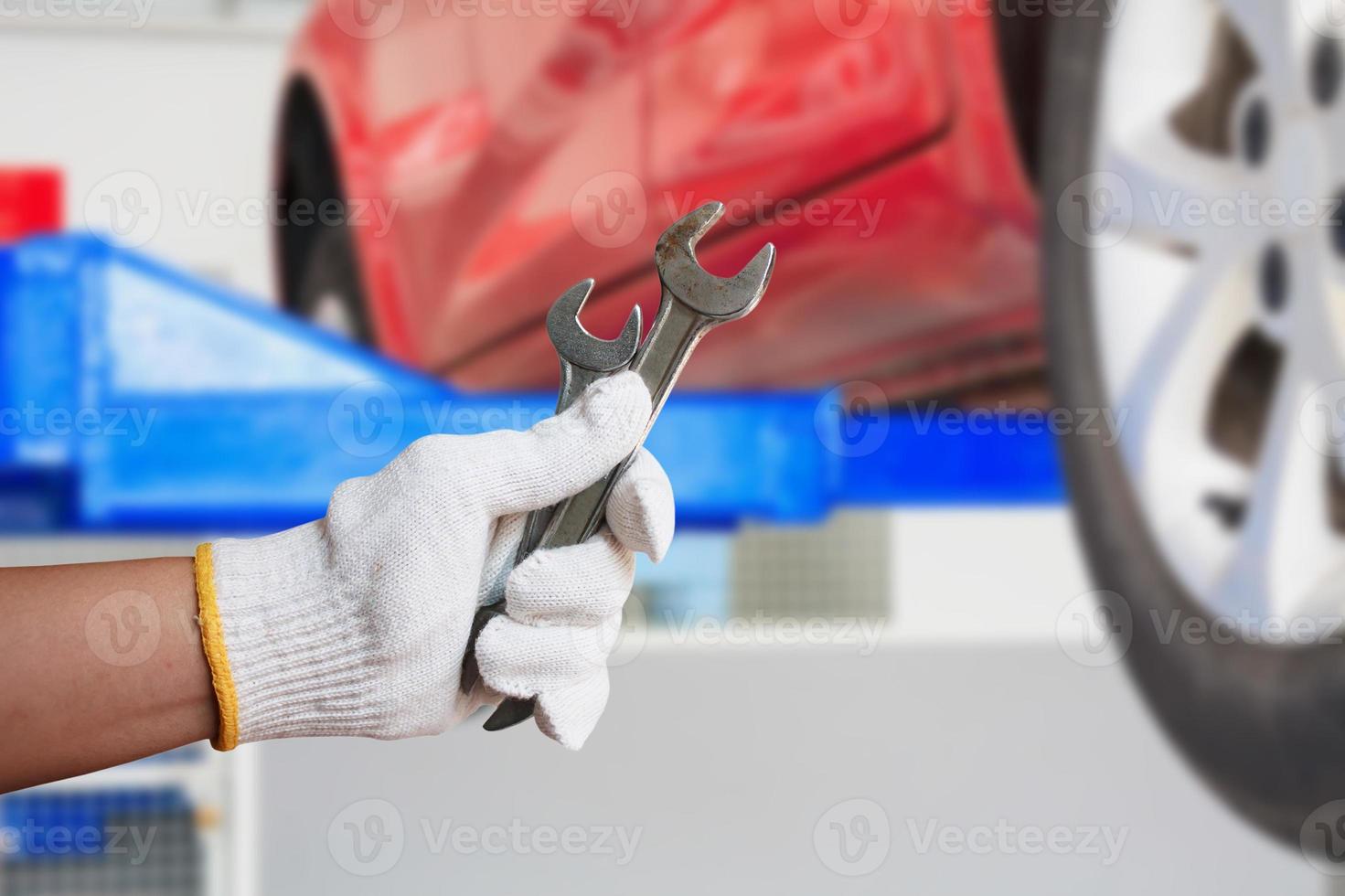 Car mechanic holding wrench at the car repair garage photo