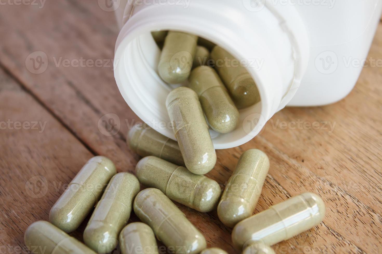 Herbal capsules spilling out of a bottle photo