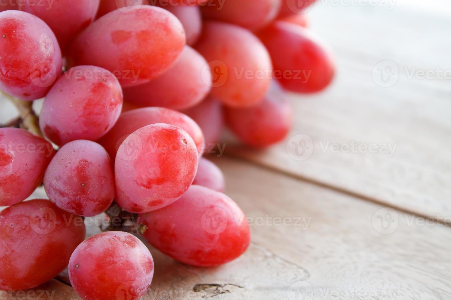 uvas rojas sobre fondo de madera foto