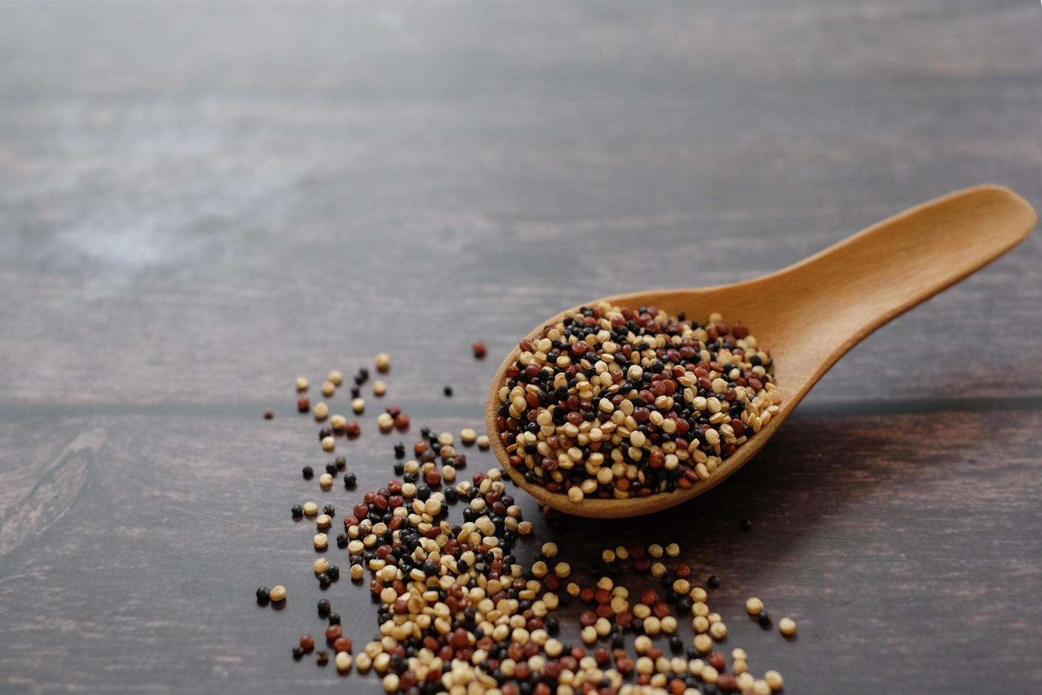 Quinoa seeds in the wooden spoon on wooden table background.  Quinoa is a good source of protein for people following a plant-based diet. photo