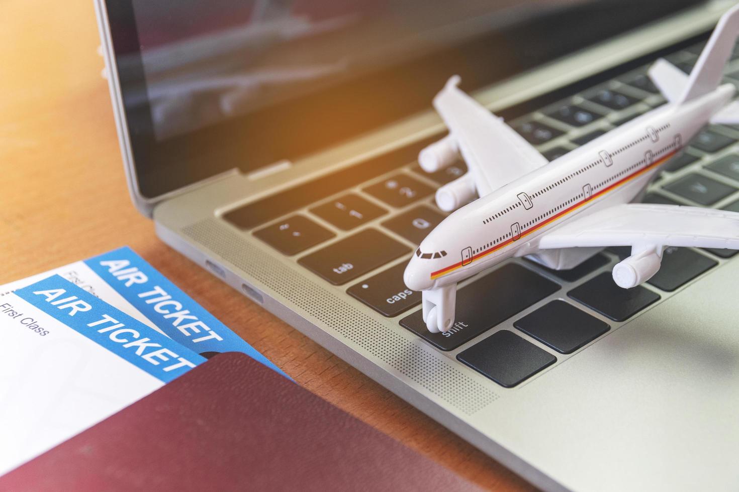 Air tickets and passports near laptop computer and airplane on table. Online ticket booking concept photo