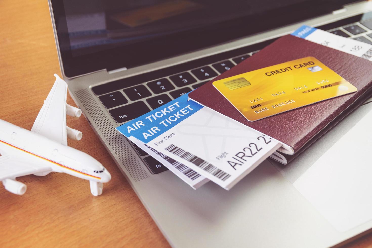 Air tickets and passports near laptop computer and airplane on table. Online ticket booking concept photo