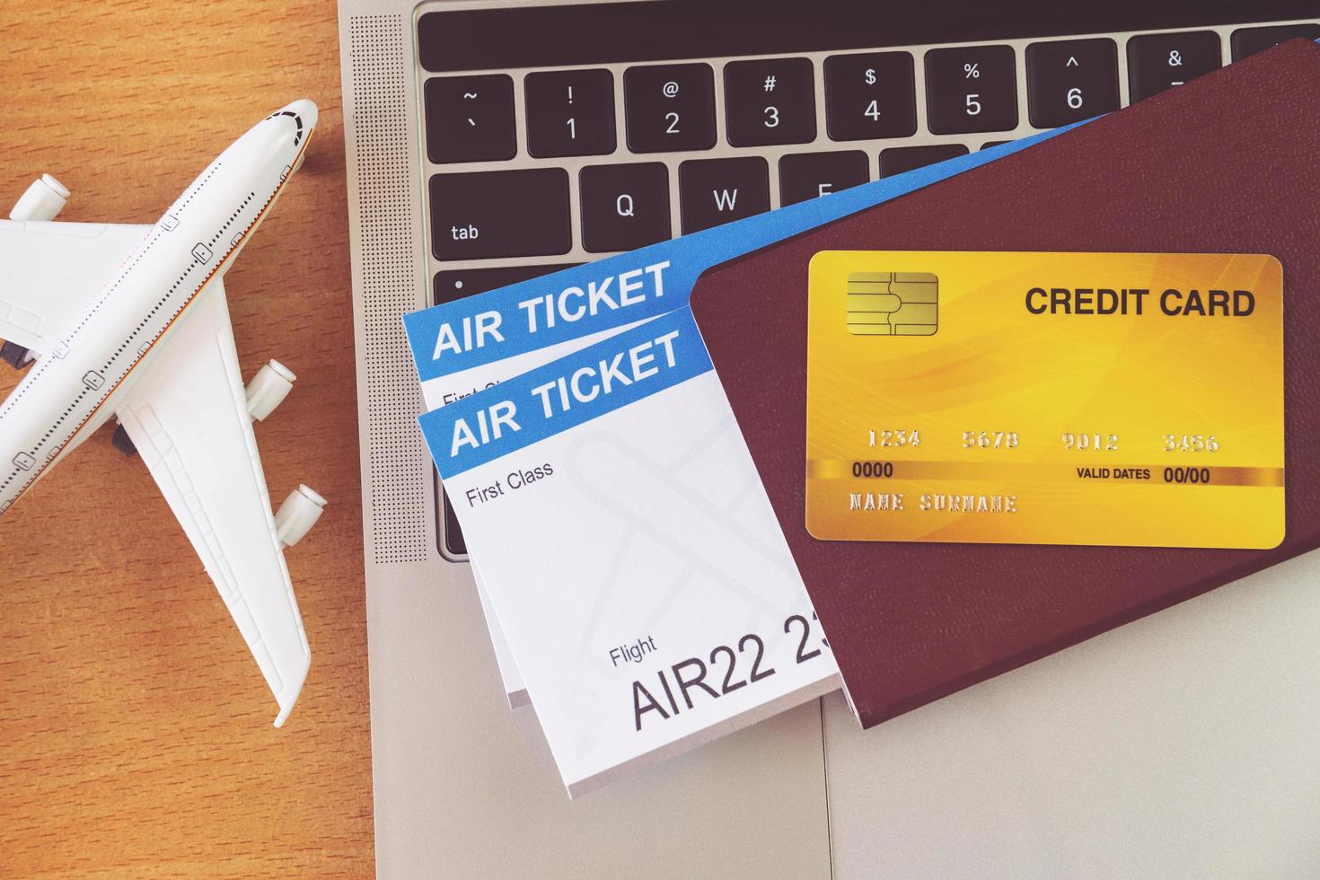 Air tickets and passports near laptop computer and airplane on table. Online ticket booking concept photo