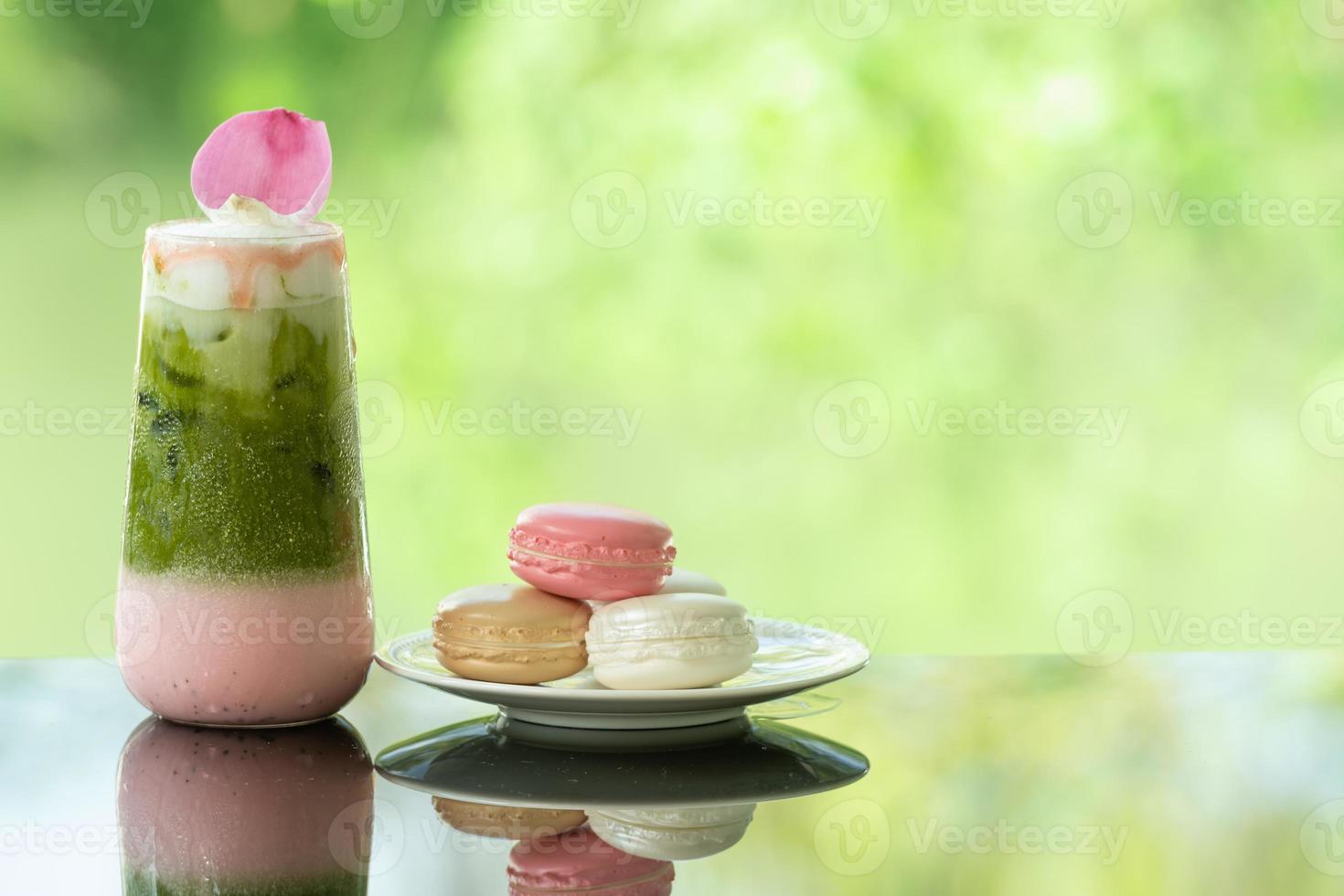 Primer plano de un delicioso y jugoso té verde con leche fresca sobre una mesa de cristal de fondo de reflexión de hojas borrosas foto